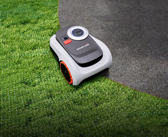 Navimow i105E robot lawn mower on grass next to stone.
