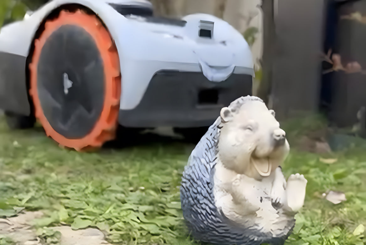 Navimow i110E robot lawn mower beside a cute hedgehog figurine.