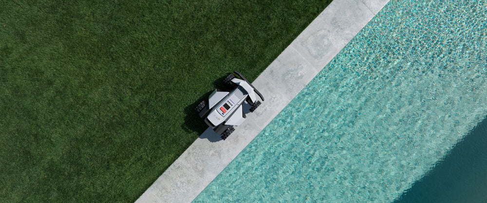 Navimow i110E robot lawn mower on grass near a pool.