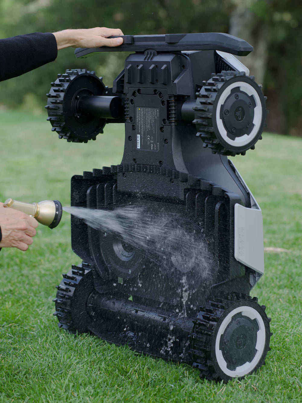 Navimow i110 robot lawn mower being washed with a hose.
