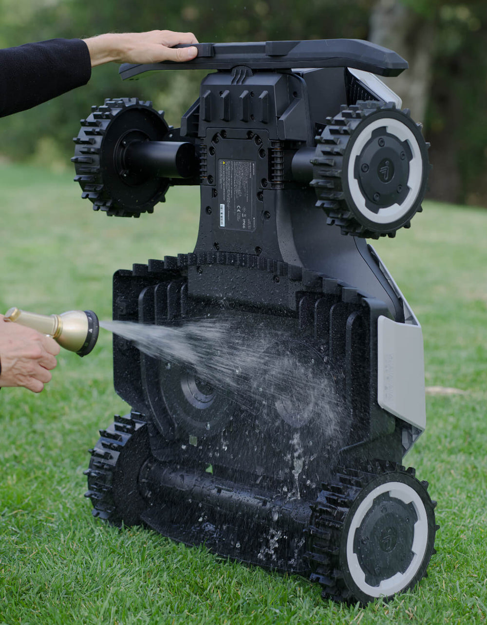 Navimow i110 robot lawn mower is being washed with water.